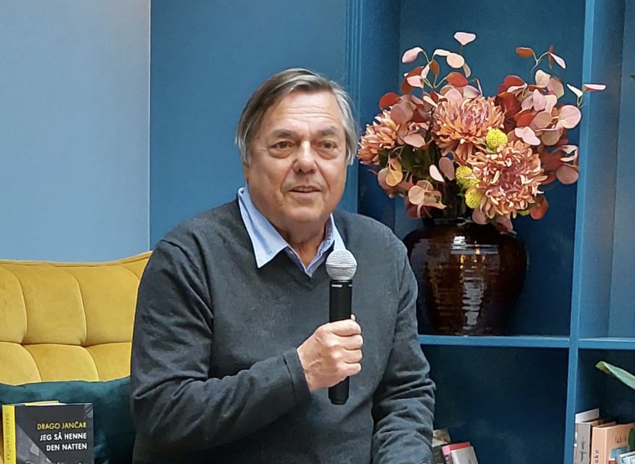 Drago Jančar sitting in the Library holding microphone