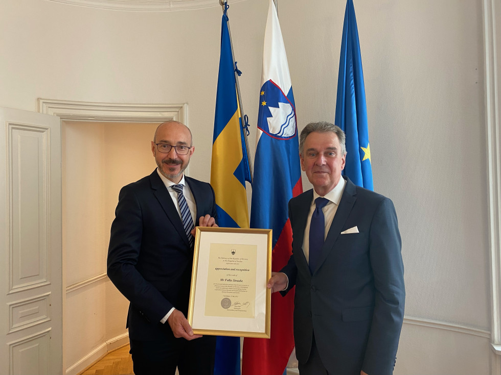 veleposlanik stoje podaja priznanje konzulu, v ozadju švedska, slovenska in evropska zastava