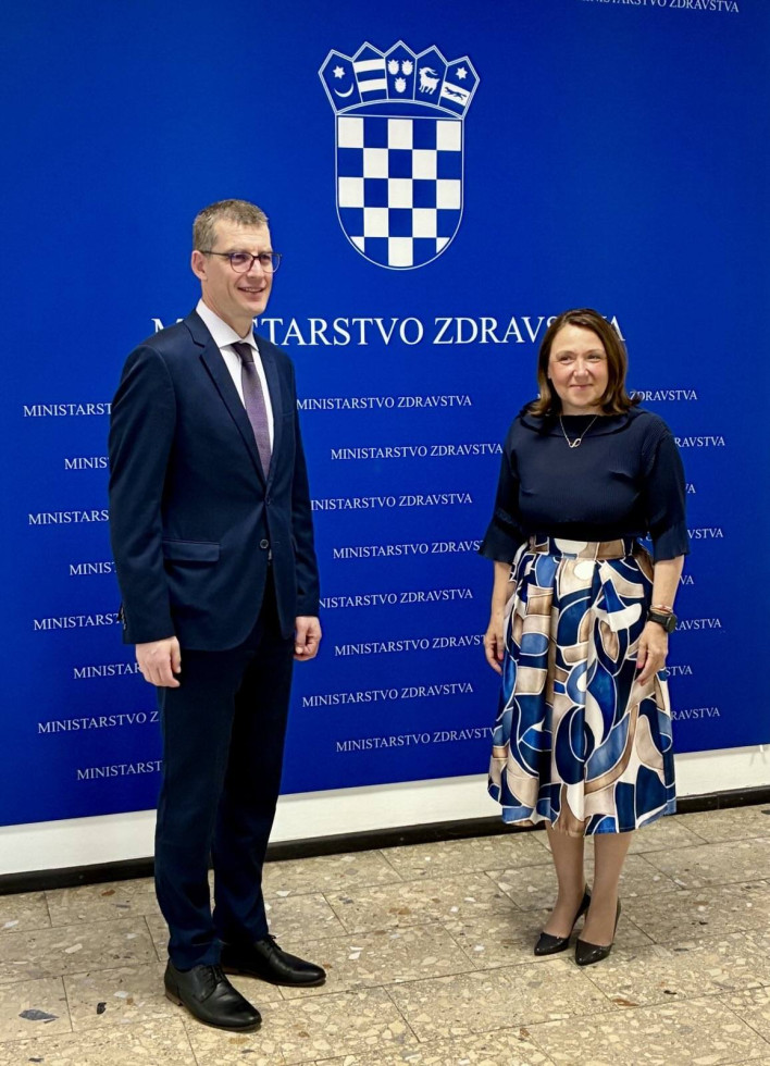 Veleposlanik Gašper Dovžan in ministrica Irena Hrstić stojita pred panojem
