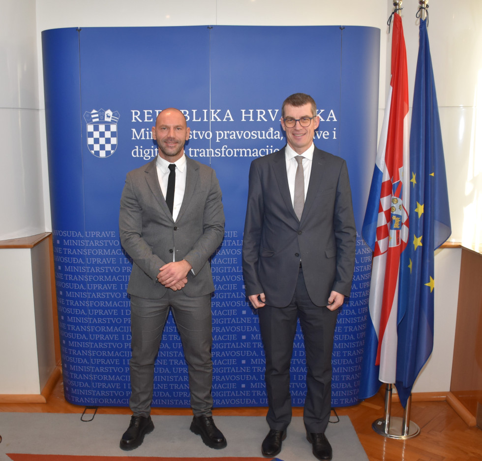 Veleposlanik Dovžan in minister Habijan stojita pred zastavami