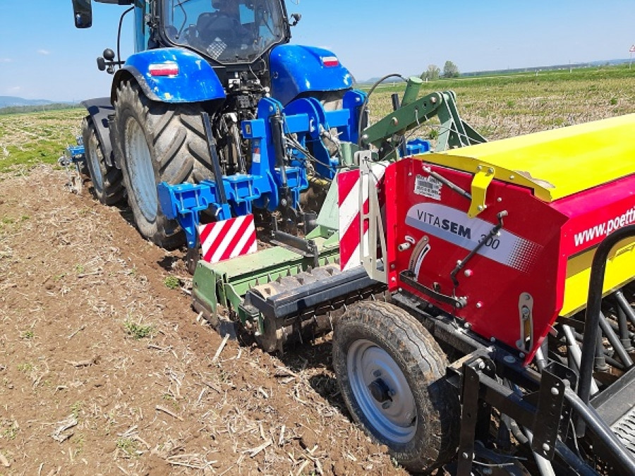 Pogled na traktor s priključkom med delom na kmetiji. 