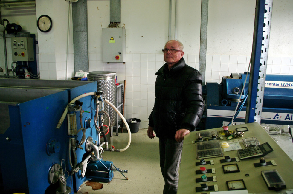 Oseba stoji ob opremi za stiskanje oljčnega olja.