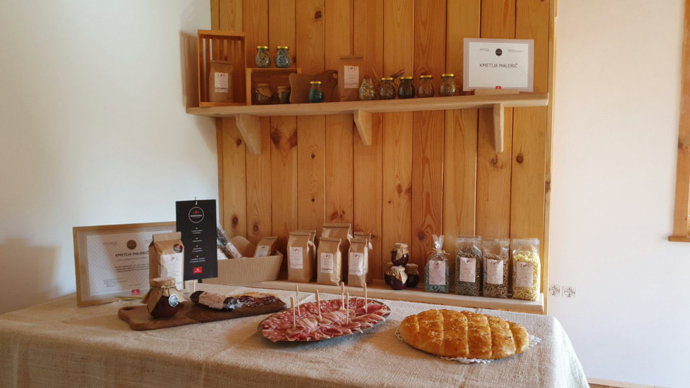 Več izdelkov je postavljenih na mizo in leseno polico. 