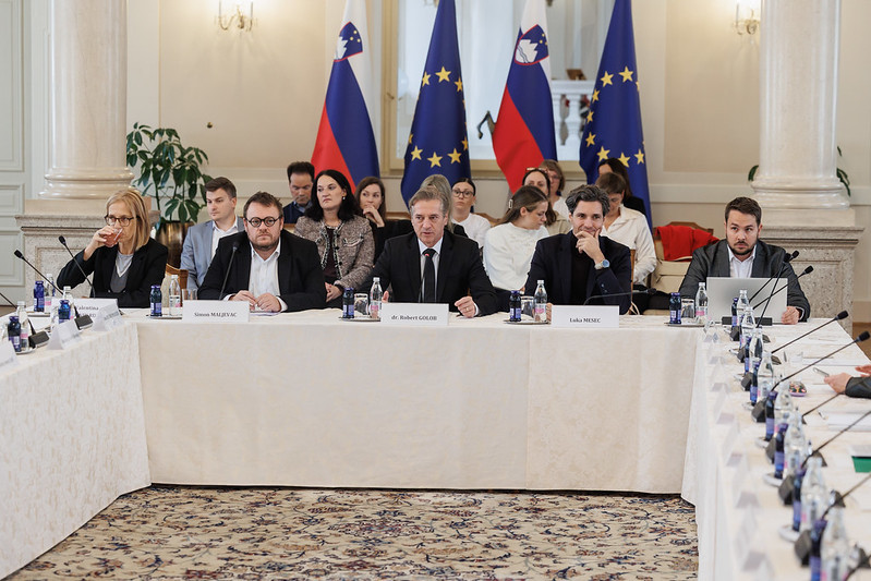 moški za mizo z zastavami v ozadju