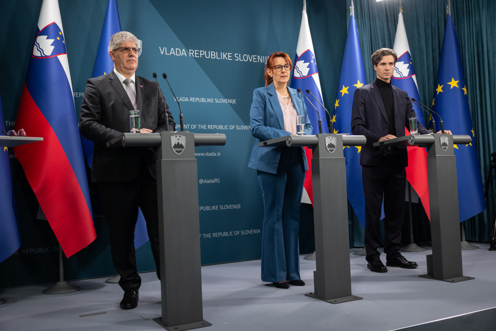 three persons standing on stage behind the microphones
