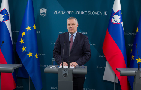 20260409 01530976 (moški za govorniškim pultom, ob straneh zastavi)