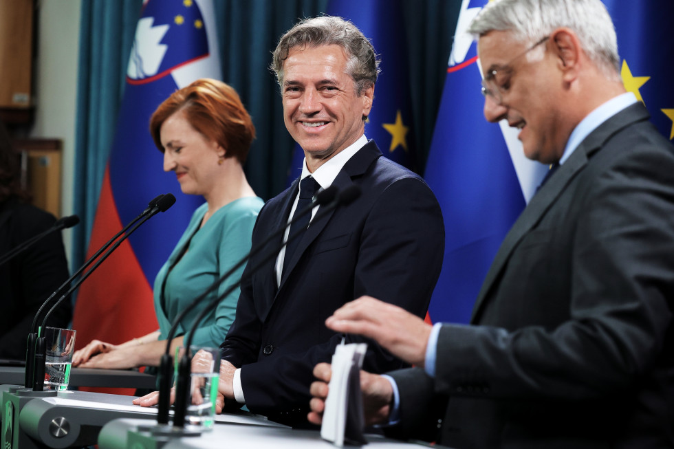 Predsednik vlade, minister in ministrica za govorniškim pultom.