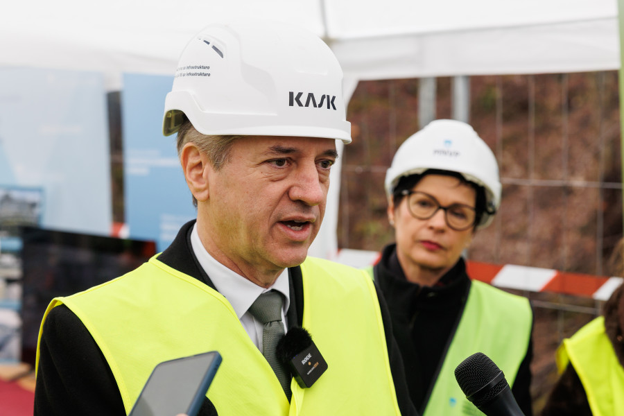 Predsednik vlade pred mikrofonom, za njim evropska komisarka Marta Kos