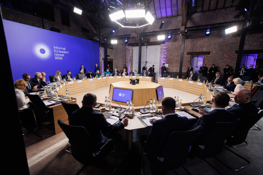 Udeleženci za omizjem. Pred sabo imajo mikrofon, vodo in sok. Za njimi velik LED zaslon in napis: Informal EU Leaders’ Retreat 2026.