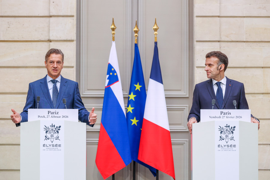 Predsednika vlade za govornicama, v sredini pa zastave