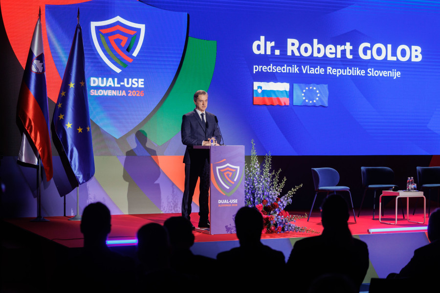 Robert Golob stoji na odru za govornico, v ozadju je napis z njegovim imenom, slovenska in evropska zastava ter emblem konference.