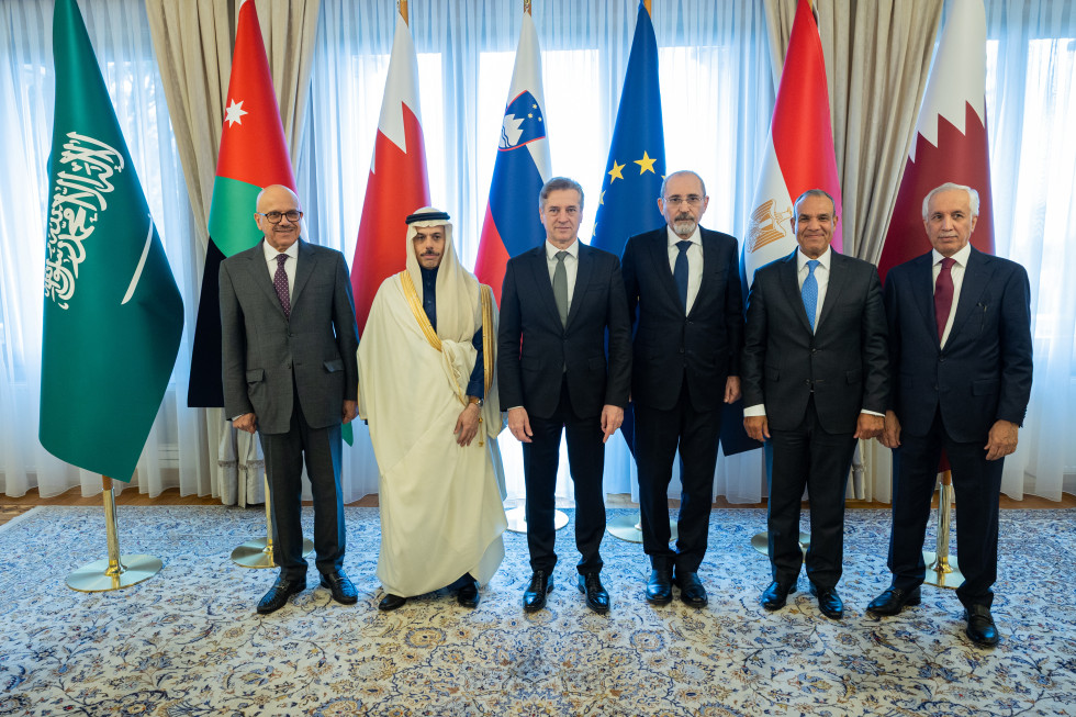 Robert Golob and Arabic ministers of foreign affairs are standing in front of flags and a window.