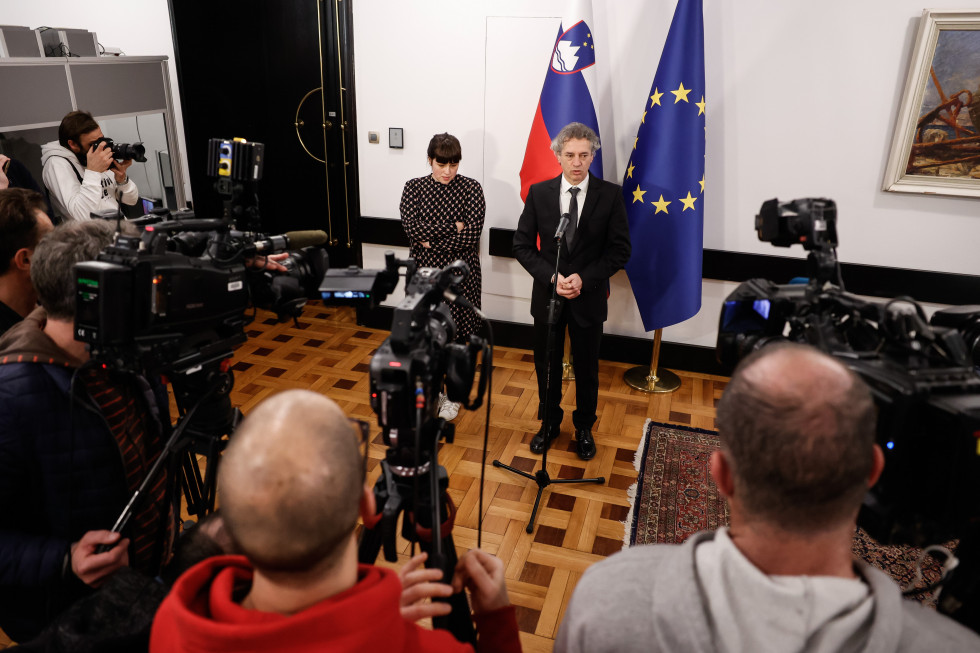 Predsednik vlade in Nike Kovač, ki bo vodila strateški svet za preprečevanje sovražnega govora, na novinarski konferenci. V ozadju zastave.