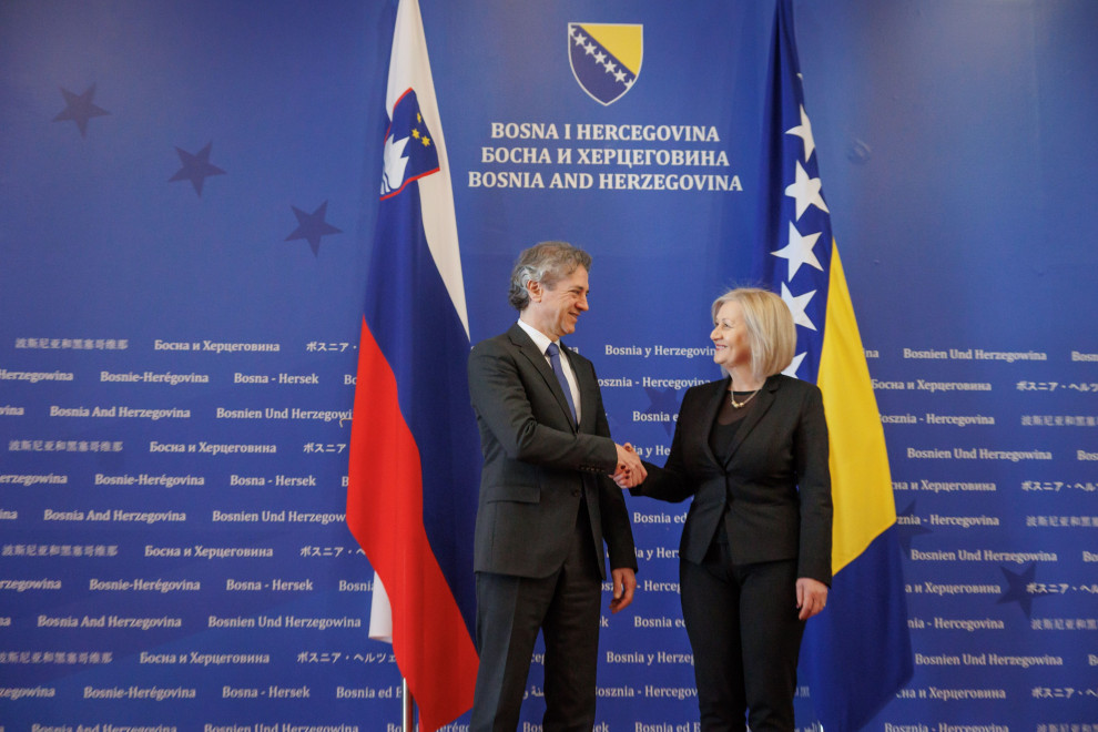 Prime Minister Robert Golob and Borjana Krišto, Chairwoman of the Council of Ministers of Bosnia and Herzegovina, shake hands in front of the flags