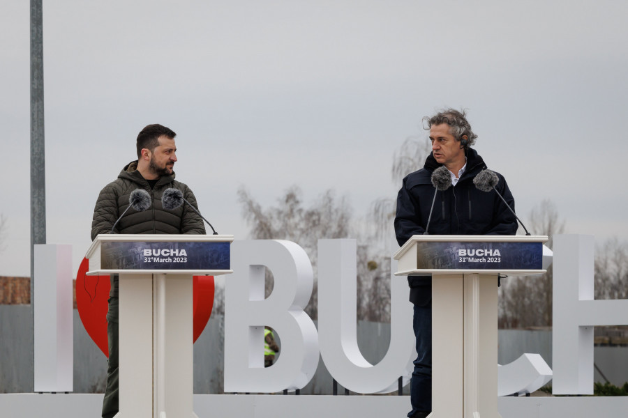 Predsednik vlade Robert Golob in ukrajinski predsednik Volodimir Zelenski na spominski slovesnosti v Buči v spomin na civilne žrtve vojne. Golob in Zelenski stojita za govorniškim pultom.