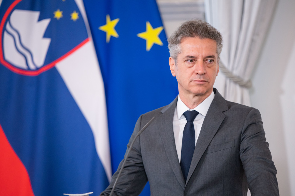 Premier dr. Robert Golob, ob slovenski in evropski zastavi