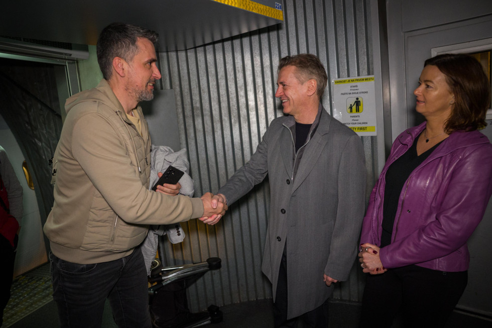 Predsednik vlade se rokuje s potnikom. Ministrica stoji ob strani.