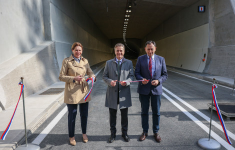 PV tretja razvojna os 1 12032026 (Robert Golob, Alenka Bratušek, and Andrej Ribič are standing on the road in front of the tunnel, holding scissors and ribbons.)
