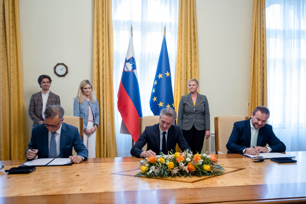 Predsednik vlade in poslanca obeh manjšin podpisujejo dogovor.