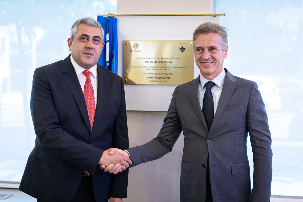 Robert Golob and Zurab Pololikashvili are standing and shaking hands, with a plaque in the background.