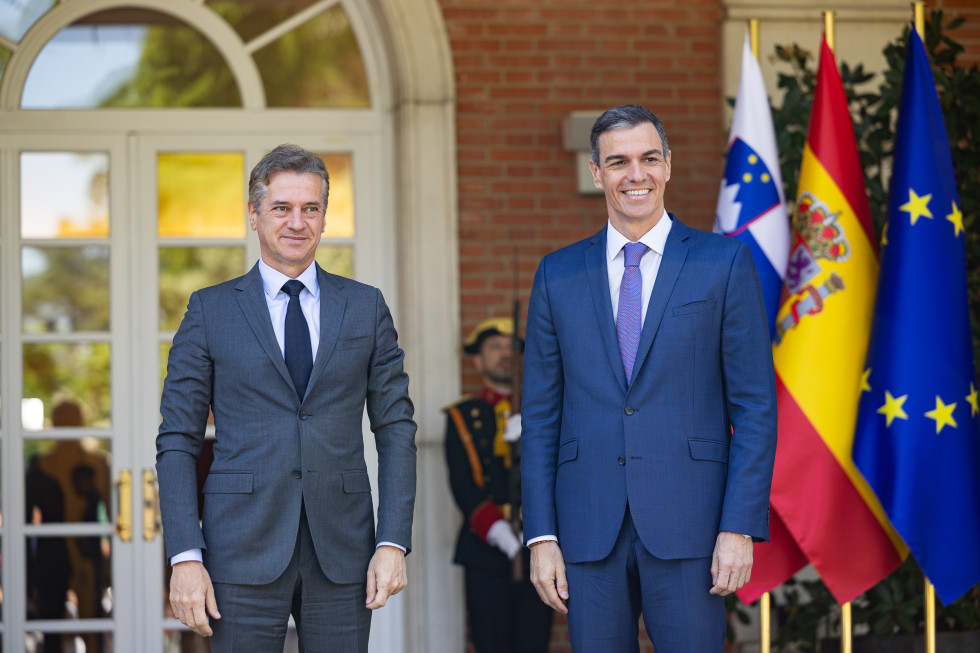 Robert Golob in Pedro Sánchez stojita, v ozadju so zastave, častna garda in odprt vhod v stavbo.