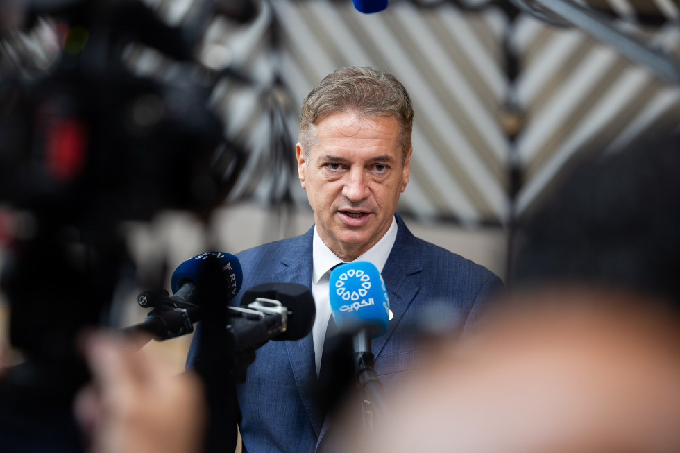 Predsednik vlade stoji pred mikrofoni in kamerami in odgovarja na vprašanja