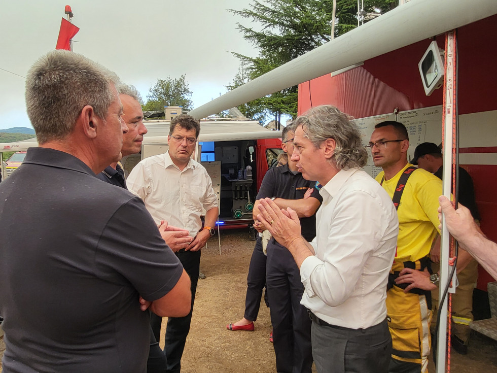 Prime minister, firefighters, European Commissioner stand in a circle and discuss