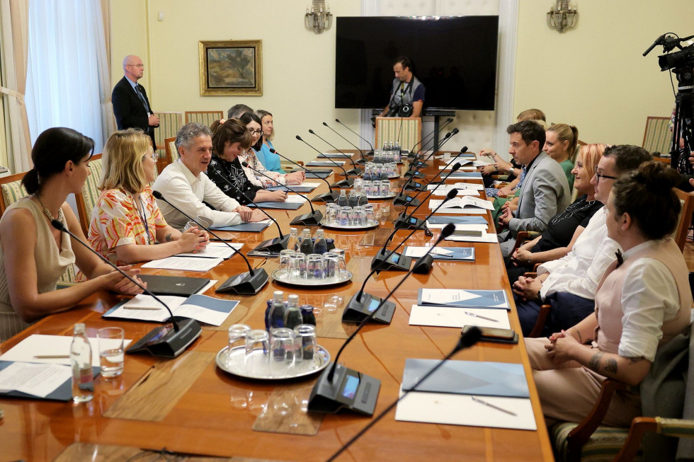 Člani Strateškega sveta za preprečevanje sovražnega govora sedijo za omizjem, med njimi predsednica sveta Nika Kovač, premier, ministrici za pravosodje in digitalno družbo