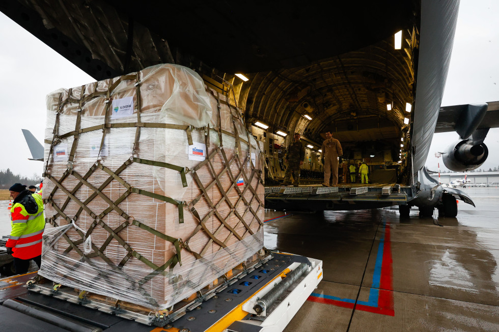 V plastično folijo in mrežo ovit paket humanitarne pomoči stoji na paletah pred vkrcanjem na letalo.