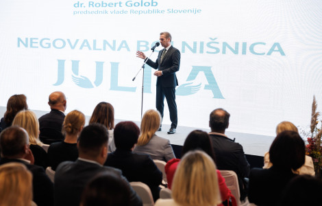 54790410487 2b18d79f25 o (Robert Golob stands on stage behind the microphone, with the participants of the hospital opening ceremony in the foreground. )