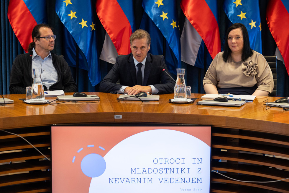 Robert Golob in udeleženci seje sedijo za okroglo mizo, v ozadju so zastave.