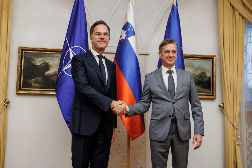 Predsednik vlade in generalni sektretar NATA pred zastavami