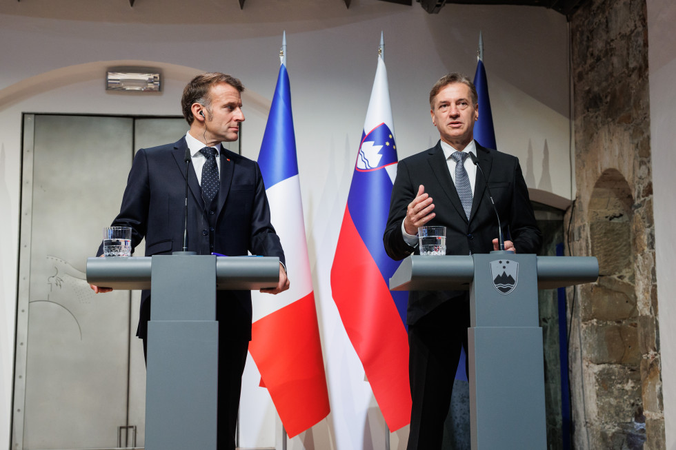 Emmanuel Macron in Robert Golob stojita za govornicama, v ozadju so zastave.