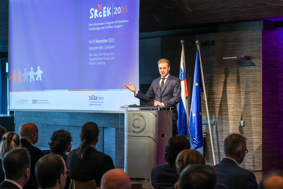 Predsednik vlade stoji za govorniškim pultom in nagovarja udeležence kongresa