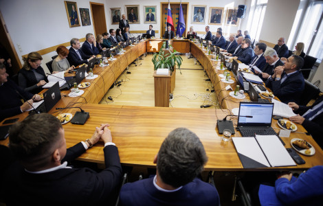 54949564033 e01e1155b3 k (Men and women are seated at a long table, with laptops in front of them and flags at the end of the room.)