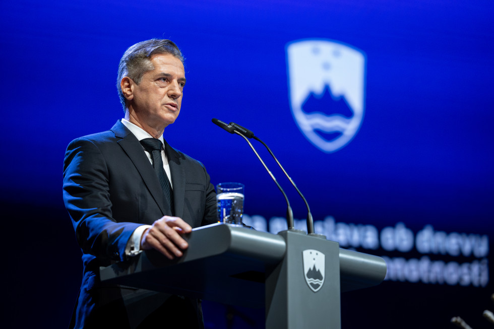Robert Golob stoji za govornico, v ozadju je slovenski grb.