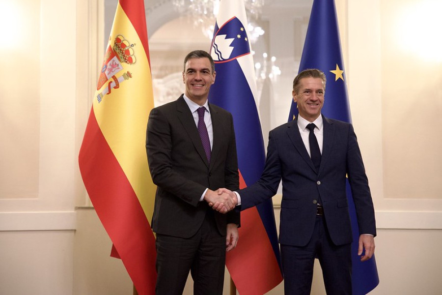 Spanish and Slovenian prime ministers shake hands, with flags in the background