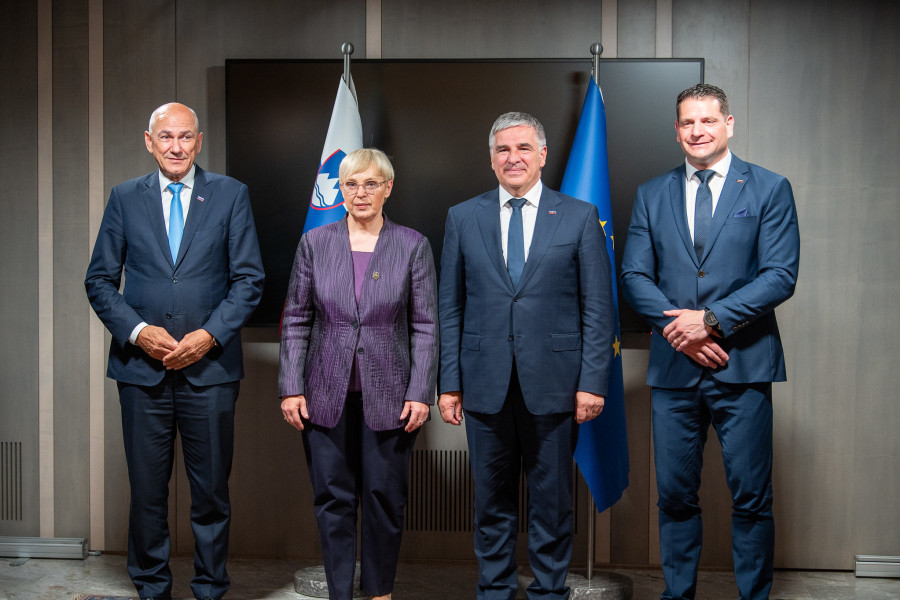 Four people standing in front of Slovenian and European flag and posing for photos