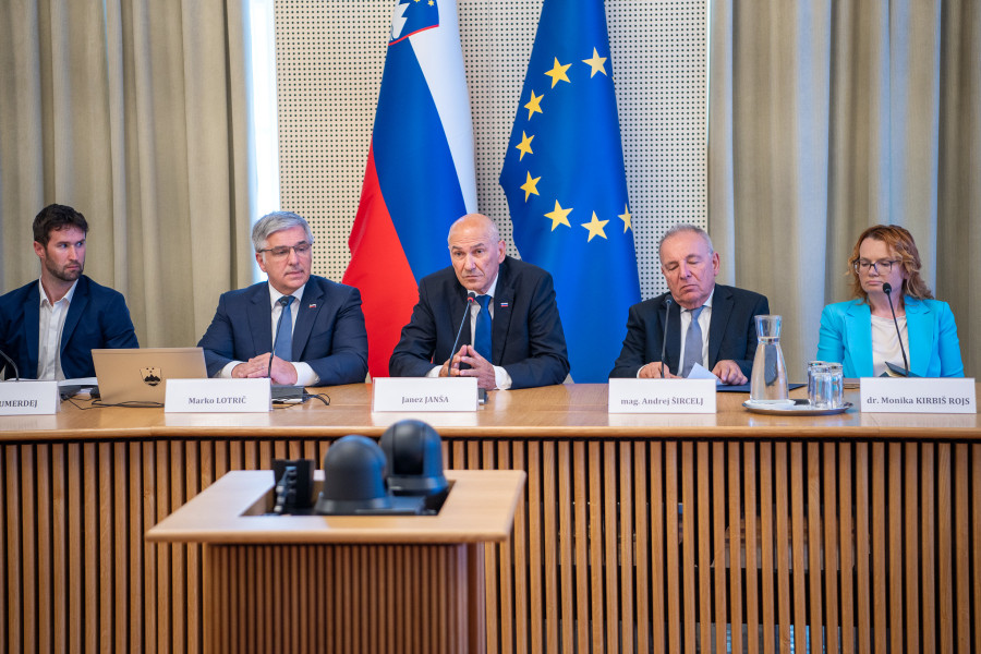 Panel of five people at a conference table with Janez Janša center; Slovenian and EU flags in the background.