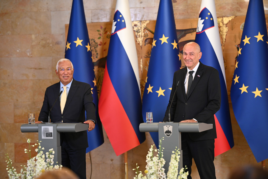 Janez Janša and António Costa are standing behind the lecterns, with pictures and flags in the background.