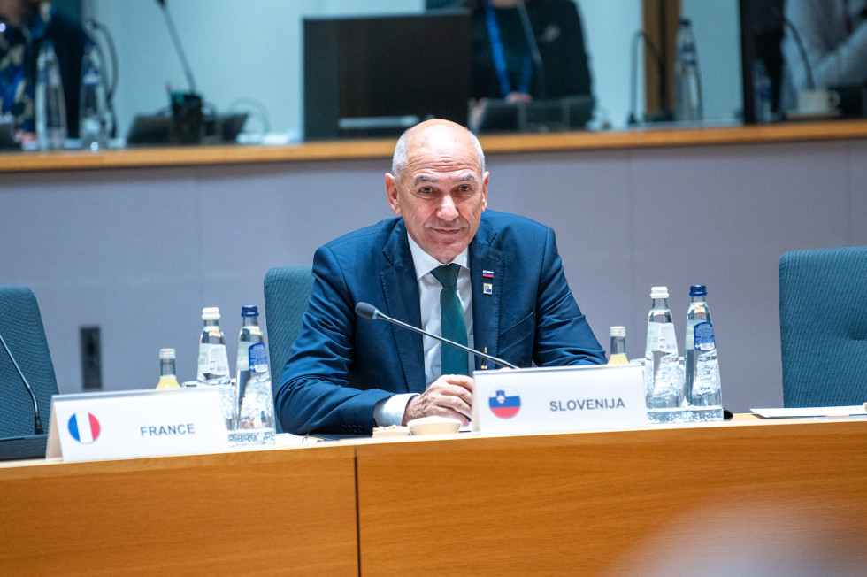 Predsednik vlade za delovno mizo, pred njim namizni napis Slovenija