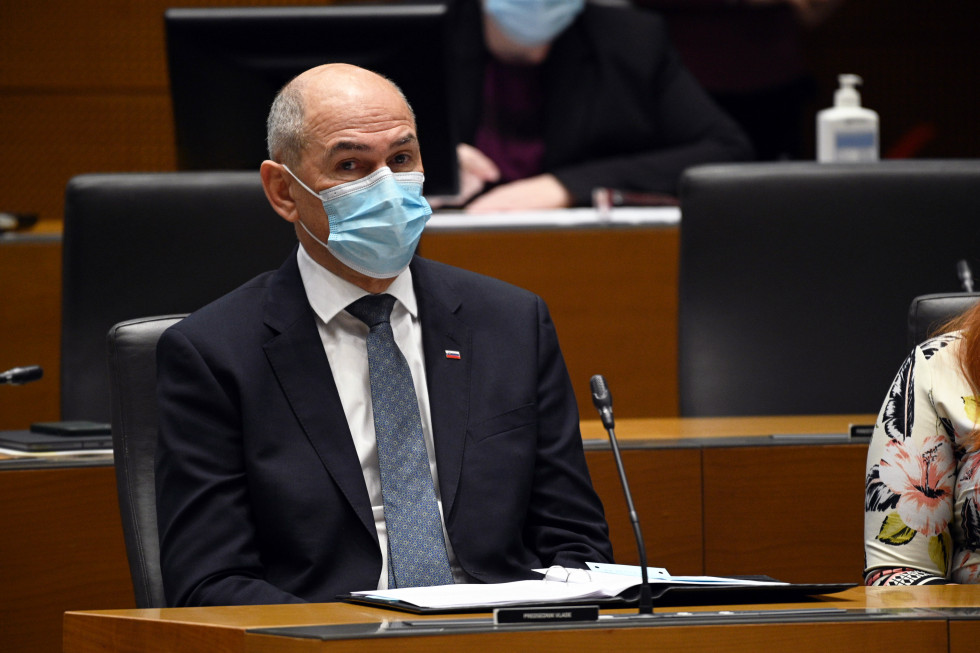 Janez Janša sedi v klopi Državnega zbora, na obrazu ima masko.