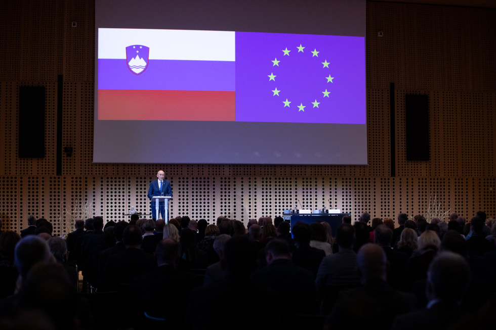 Predsednik vlade Janez Janša za govornico, v ozadju zastava Slovenije in EU