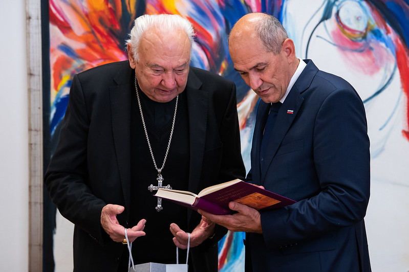 Janez Janša in Jurij Bizjak si ogledujeta knjigo.