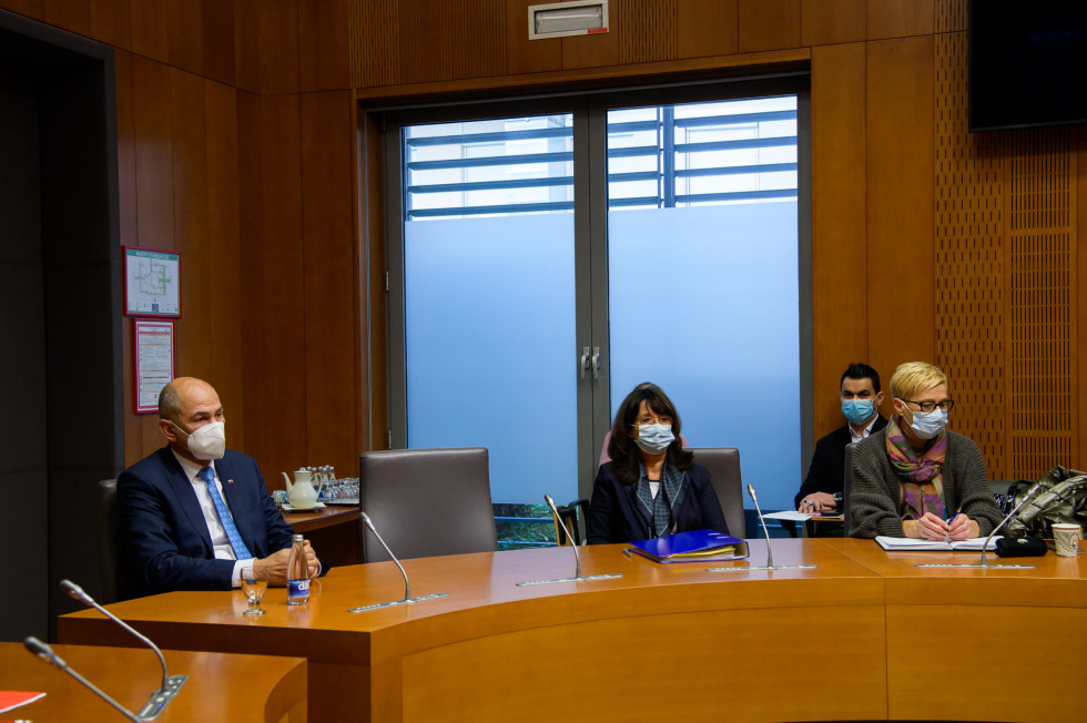 Predsednik vlade sedi za konferenčno mizo, na desni strani udeleženki seje.