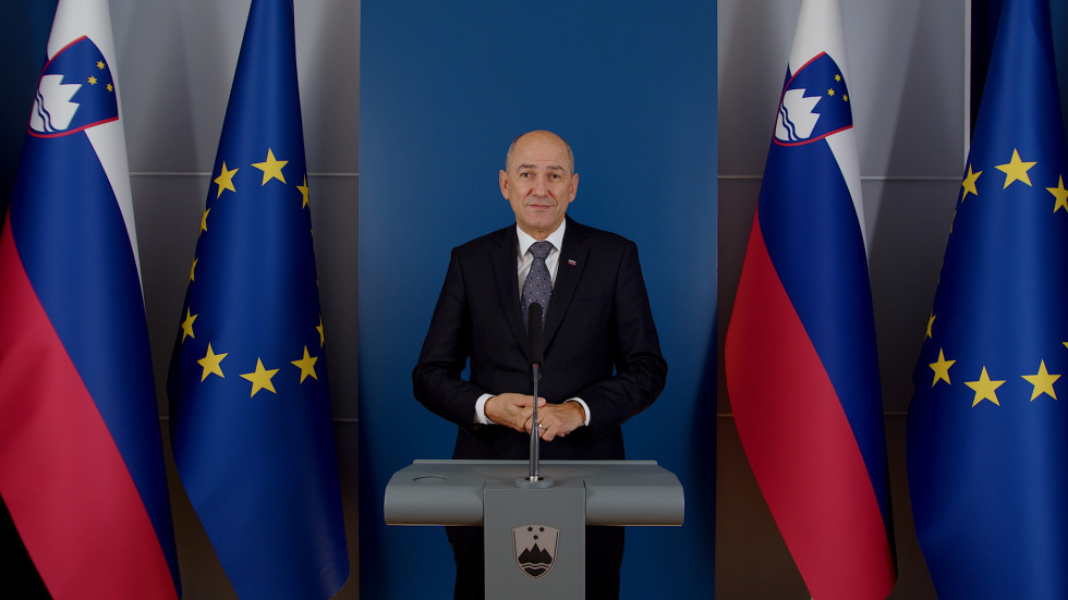 Predsednik vlade za govornico, v ozadju zastave Slovenije in EU