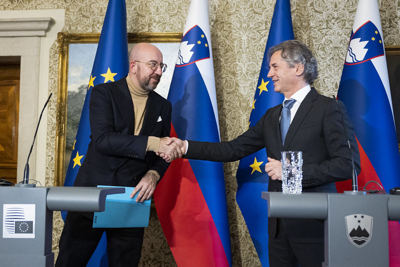 European Council President Charles Michel and Prime Minister Robert Golob shake hands at the lectern in front of the flags