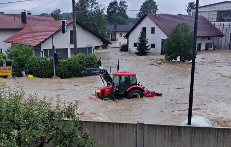 Poplave 2023 (Houses stand in water during the 2023 floods, with a red tractor in the middle.)