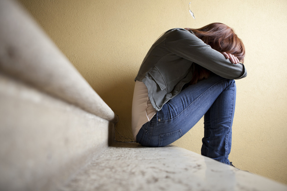 Sad woman sitting with hair over face.