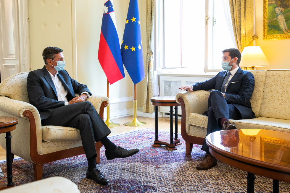Borut Pahor in Mark Boris Andrijanič med pogovorom sedita na foteljih, v ozadju sta zastavi Slovenije in EU